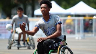 Junior wheelchair softball player pitching ball