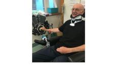 photo of Ian, an older man with glasses in a neck brace at rehabilitation.