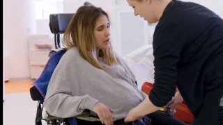 Adriana pictured in a wheelchair with a physical therapist