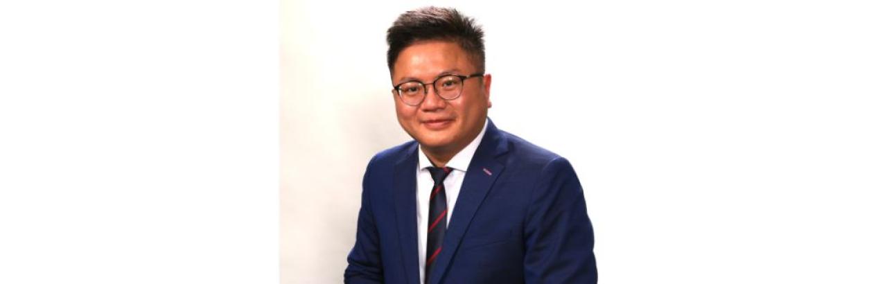 color photo of Chinese man in suit and glasses smiling