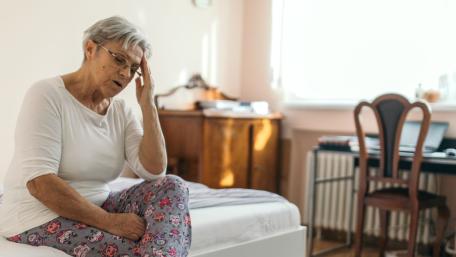 Woman sitting on bed due to vertigo