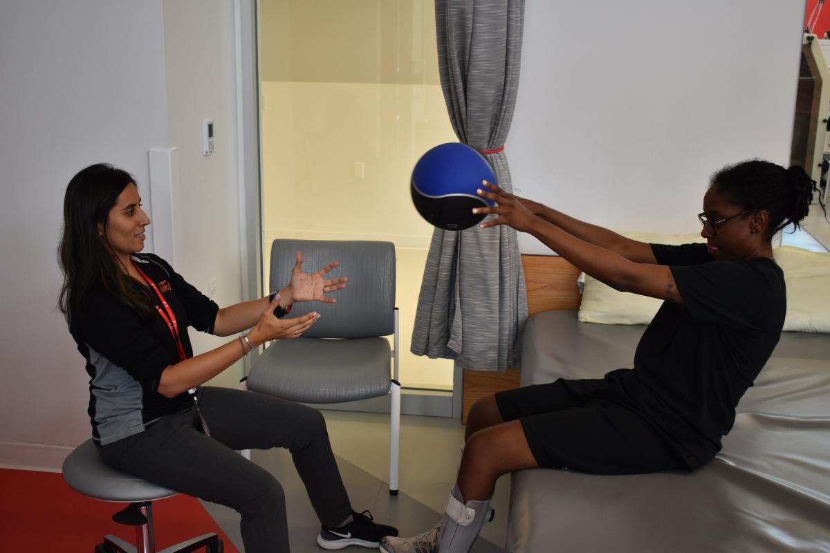 patient holds ball with hands during therapy with physical therapy