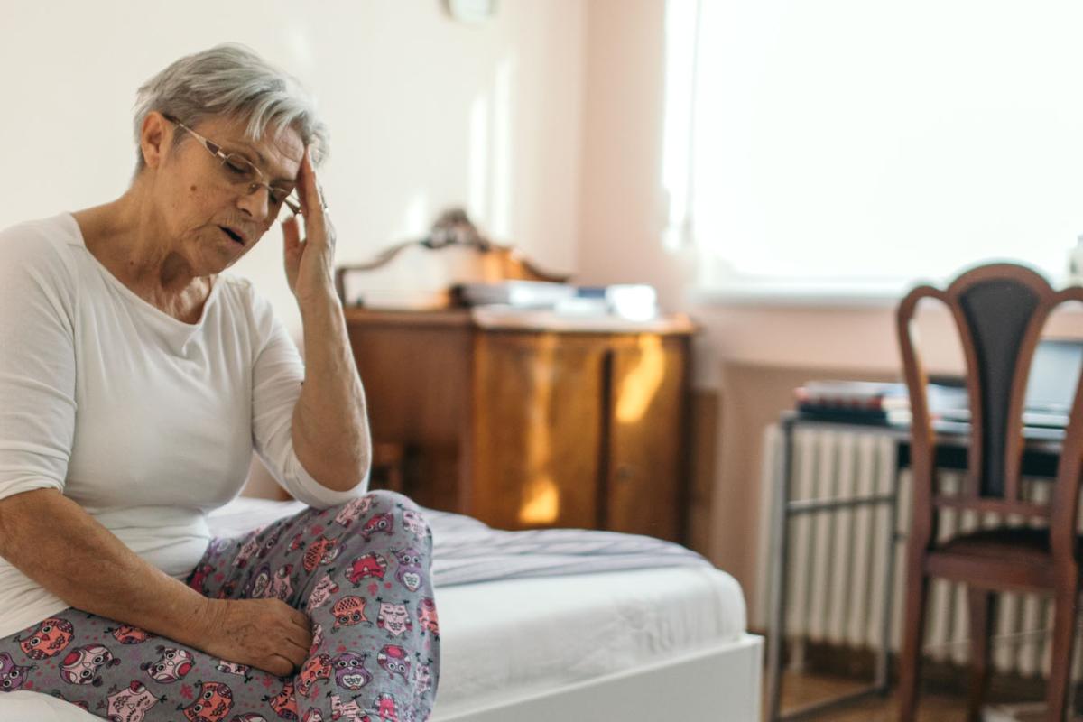 Woman sitting on bed due to vertigo