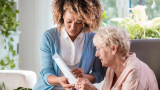 This is a picture of a black nurse and an elderly white woman working together to address the patients' care plan.