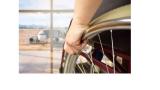 a photo of a hand holding the wheel of a wheelchair facing a window that looks out at an airplane on the tarmac