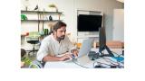 A white man with brown hair and beard sitting in a wheelchair works at a computer.